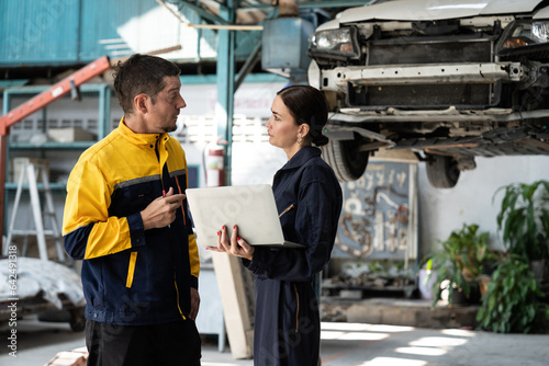 Two vehicle mechanic working together, conduct car inspection with laptop. Automotive service technician in uniform carefully make diagnostic troubleshooting to identify error. oxus photo