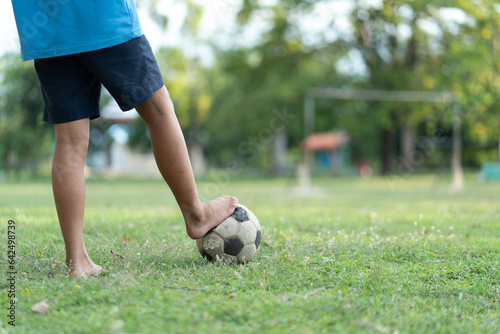 Close up of a old soccer, boy not wearing shoes ready to kicks the ball at the old football field.