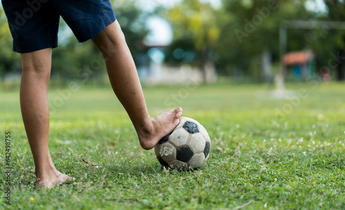 Close up of a old soccer, boy not wearing shoes ready to kicks the ball at the old football field.