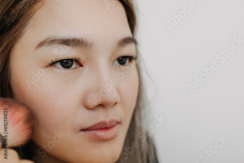 Close up of asian woman brushing her cheek face for make up.