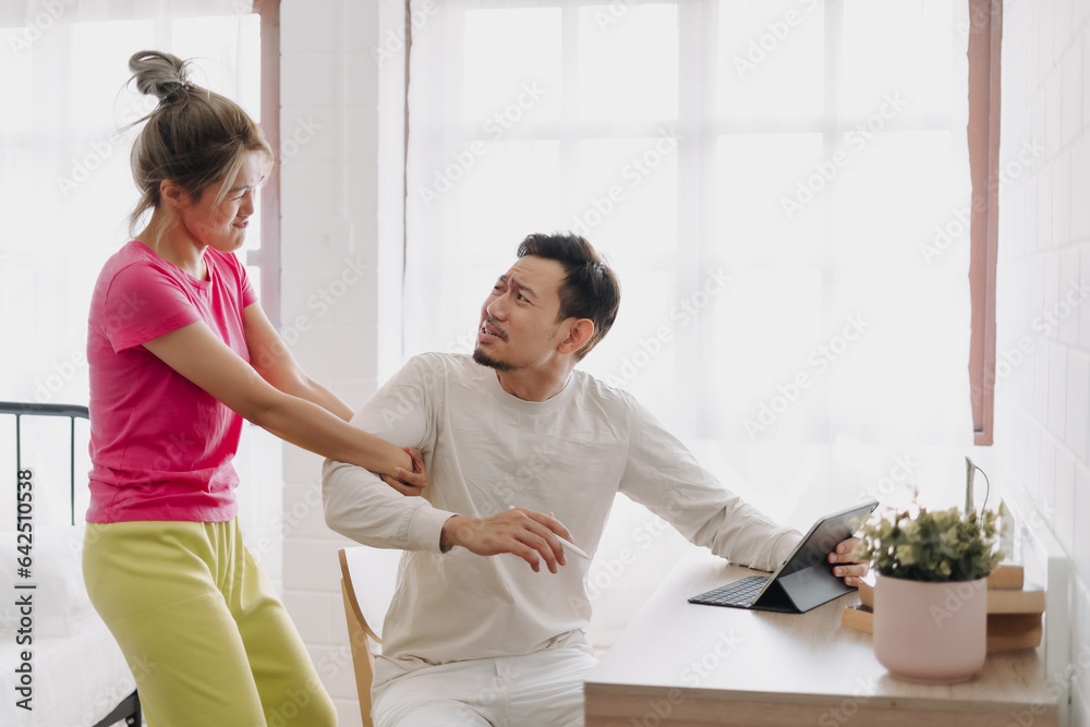 Fototapeta premium Asian wife asking husband to stop working and watching with computer tablet.