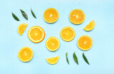Orange slices with leaves and water drops on blue background