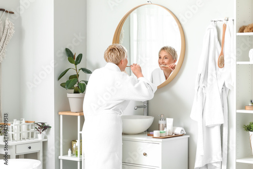 Mature woman brushing teeth...