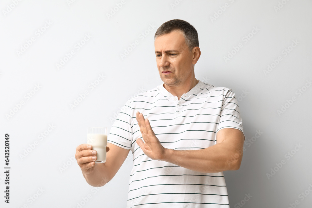 Displeased mature man rejecting glass of milk on white background Displeased mature man rejecting glass of milk on white background