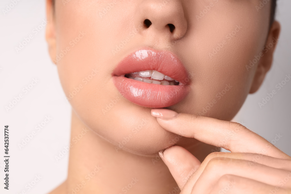 Young woman with beautiful lips on light background, closeup