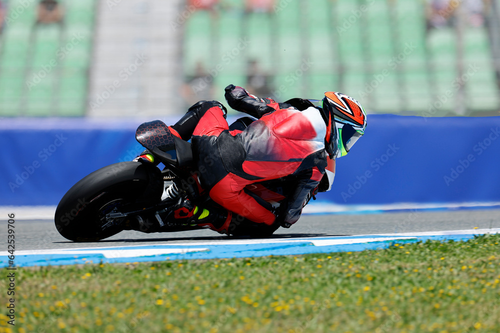 Naklejka premium motorista toma una curva en circuito 