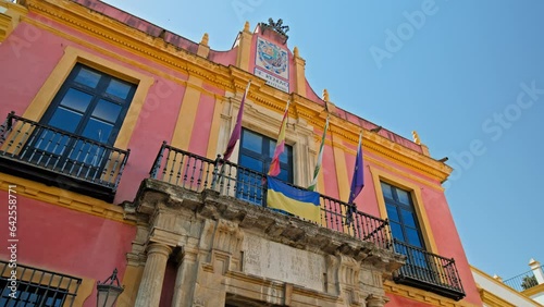 Colourful building with Spanish Ukrainian and European flags in front in Seville. The flags of Ukraine, Spain, Catalonia, and Europe by Royal Alcazar of Seville Castle