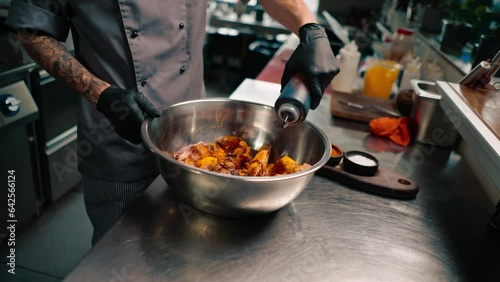 chef wearing black gloves seasoning raw chicken wings in professional kitchen of restaurant Asian cuisine