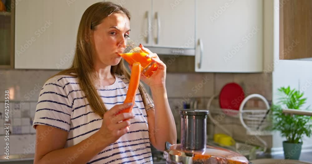 Young woman drinking freshly squeezed carrot juice in the kitchen Young woman drinking freshly squeezed carrot juice in the kitchen
