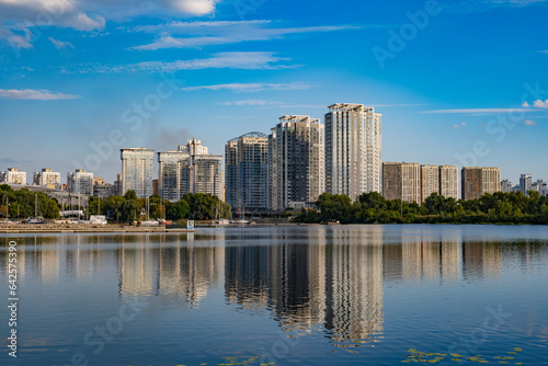 Beautiful urban summer landscape: Multi-storey buildings, river and park © Victoria