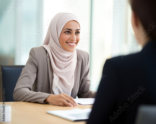Muslim woman wearing a hijab at a job interview at an office, sitting across the table from HR and the manager. Concept of job searching and career choices for minorities. Shallow field of view.