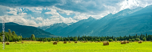Panorama of mountains behind haystacks in a farm field in British Columbia, Canada