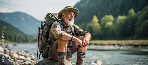 Elderly adventurer by the river heading to the mountain Senior hiker 60s active retirement Room for text