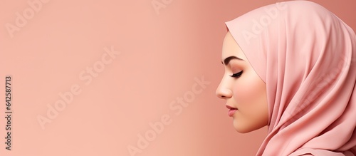 Portrait of a modest girl wearing hijab looking at space with a pink background photo