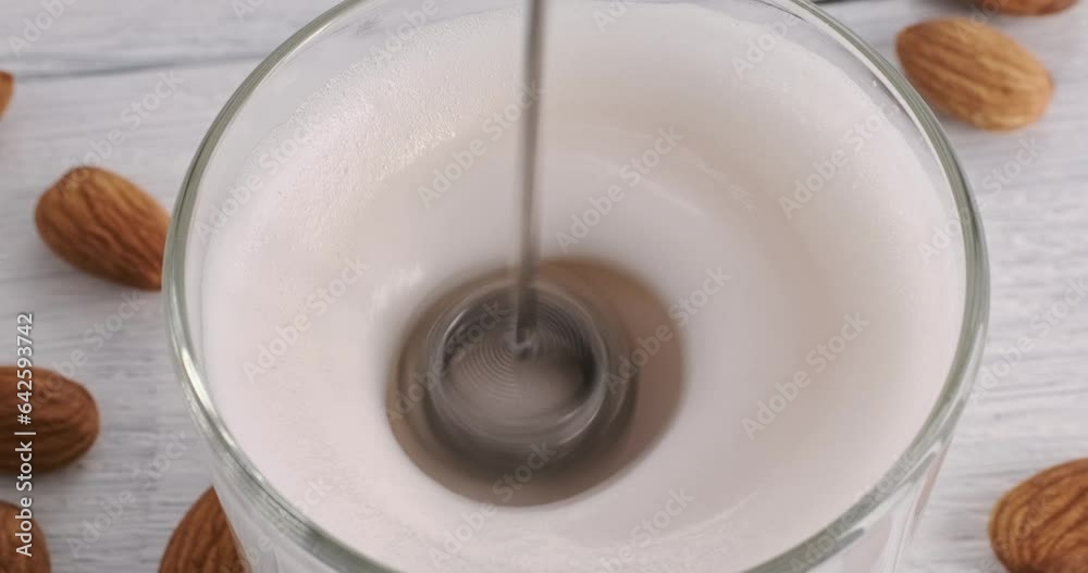 Making milk froth with electric milk foam maker, top view close-up video of automatic rotating milk frother quickly whipping vegan non-dairy drink made of almond nuts, 4k footage, hd video Making milk froth with electric milk foam maker, top view close-up video of automatic rotating milk frother quickly whipping vegan non-dairy drink made of almond nuts, 4k footage, hd video