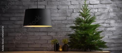 Minimalist black industrial loft style lampshade adorned with spruce branches against a white brick wall creating a close up Christmas and New Year ambiance photo