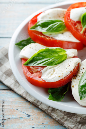 Delicious Caprese Salad with ripe tomatoes and mozzarella cheese with fresh basil leaves. Italian food. Close up