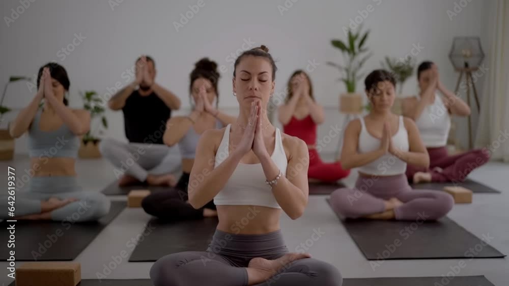 Group of diverse fitness young people practicing yoga instructor mudra exercises indoors. Concentrated meditating persons in class. Healthy lifestyle in community, wellness and daily morning routines