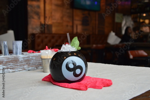  cocktail in a black billiard ball on a pink in a bright restaurant isolated
