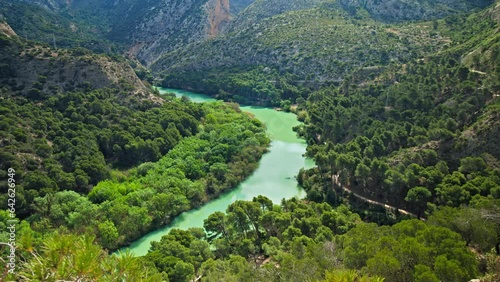 Beautiful panoramic view of a green Mountain Gorge with a Turquoise River. A mountainous scenic region with many trees and the Caminito del Rey River in El Chorro, Spain, Europe