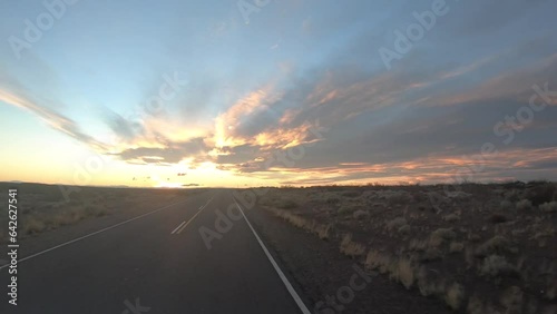 Road trip. Traveling across the arid landscape. Driving along the route under a dramatic sky with twilight colors.