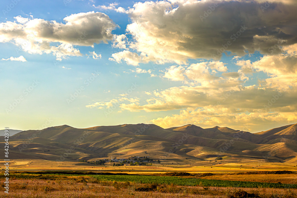 A village nestled at the foothills in Anatolia. Sunset over the golden steppe. Autumn mountain view
