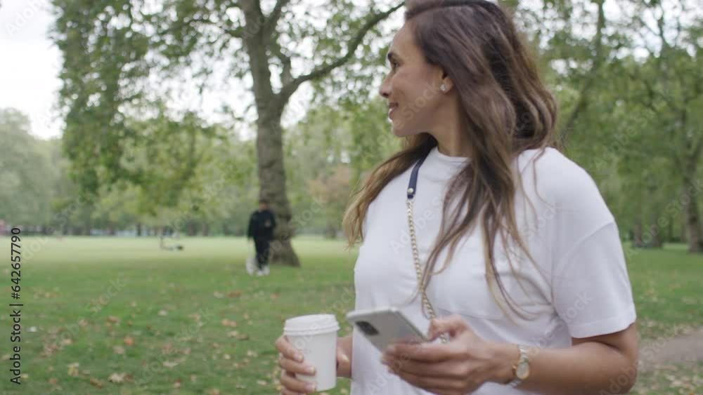 Young mixed race woman walking in the park and using her phone Young mixed race woman walking in the park and using her phone