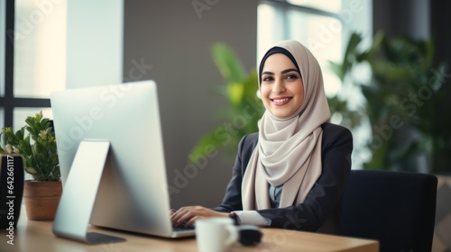 Attractive middle eastern businesswoman woman posing at her work place sitting at her desk using a computer