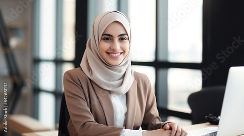 Attractive middle eastern businesswoman woman posing at her work place sitting at her desk using a computer