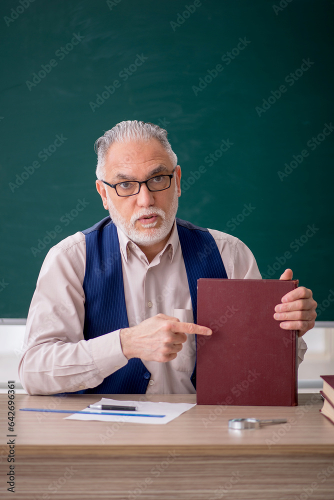 Old male teacher in front of green board Old male teacher in front of green board