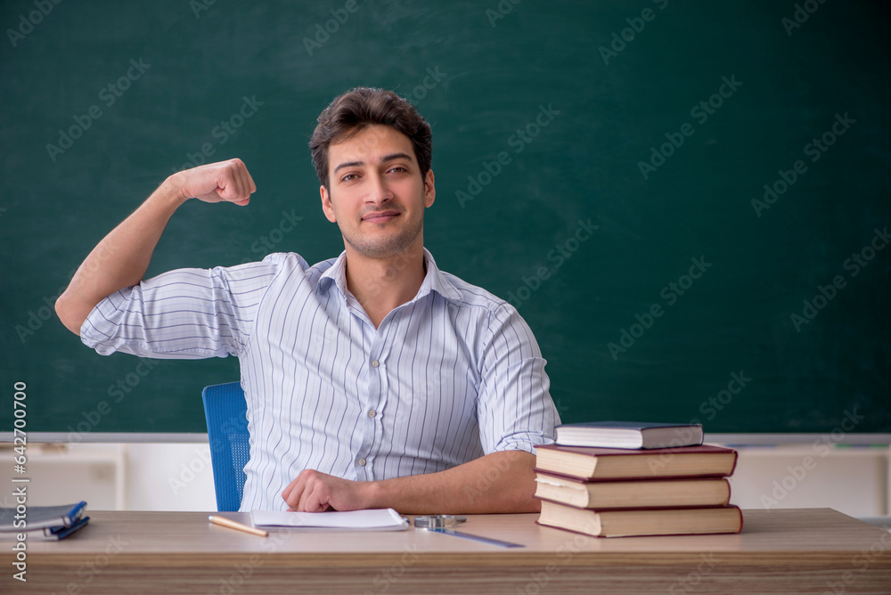 Young male teacher in front of green board Young male teacher in front of green board