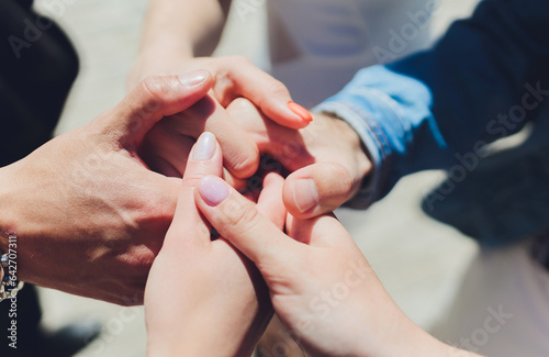 two man and three women holding hands on a table implying a polyamory relationship or love triangle. photo