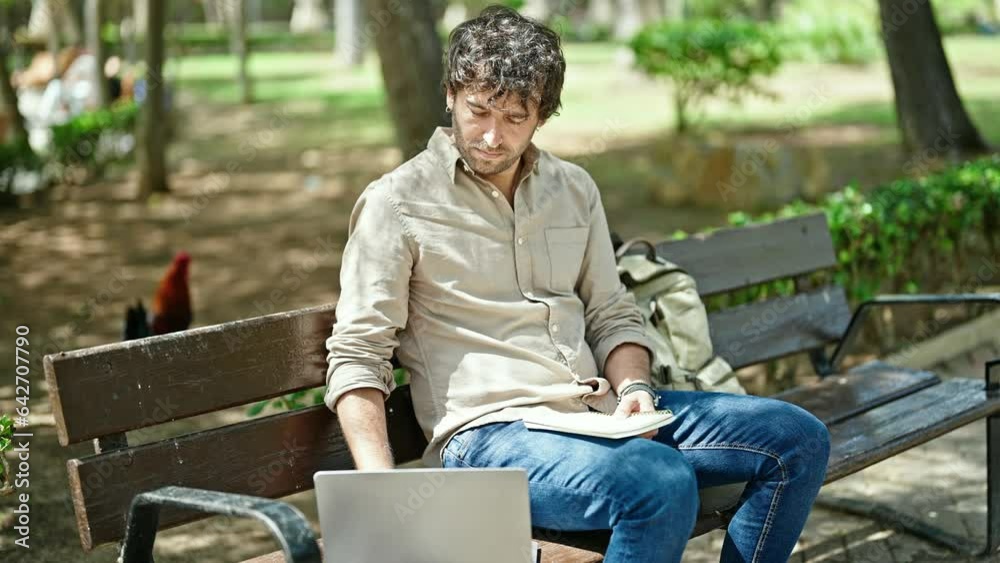 Young hispanic man writing on notebook using laptop at park Young hispanic man writing on notebook using laptop at park