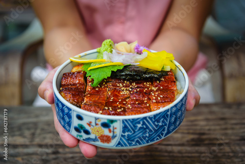 Unagi don bowl in woman hand, Japanese eel grilled with rice Japanese food. photo