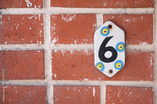 house number six. Decorative lettering on a brick wall.