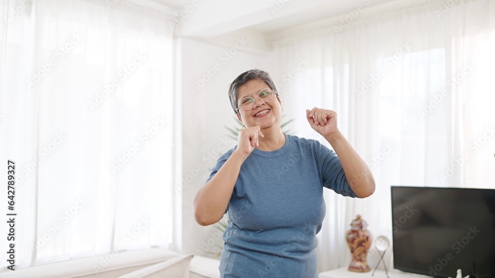 Cheerful asian elderly woman enjoy dancing in living room at home. Happy senior woman dancing and having fun. Elderly woman leisure weekend at home. Asian senior lifestyle