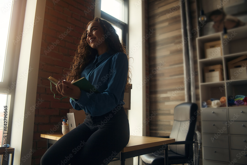Young Asian curly-haired logistics worker packs goods, collects parcels, puts things in a carton box, prepares a parcel for shipment, transports, collects donations, business owner, delivery