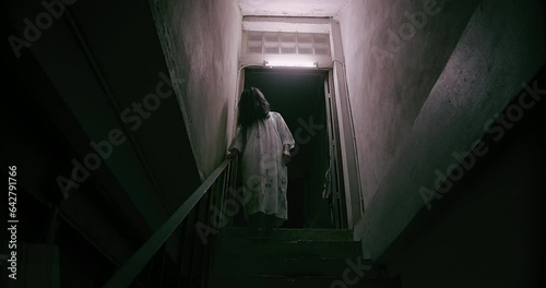 Horror scene of a mysterious Scary Asian ghost woman creepy have hair covering the face standing on staircase at abandoned house with background dark scene movie at night, festival Halloween concept photo
