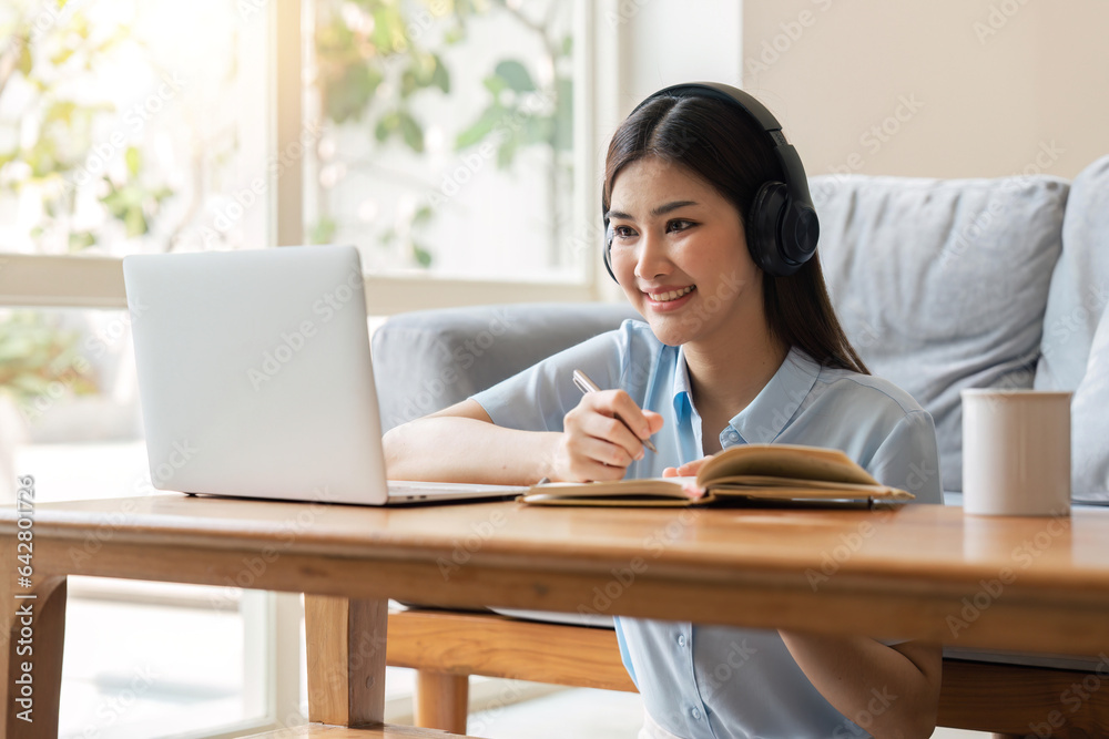 young woman working on laptop and taking notes while listening to lecture at home young woman working on laptop and taking notes while listening to lecture at home