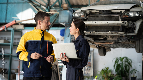 Two vehicle mechanic working together, conduct car inspection with laptop. Automotive service technician in uniform carefully make diagnostic troubleshooting to identify error. oxus photo