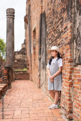 asian child or kid girl travel to portrait with brick wall in archaeological site and wat ratchaburana temple at ayutthaya and old ancient in Thailand for people tourist to study retro history