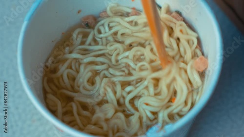 Stirring instant noodle with chopsticks in box on white background. Stirring heated instant noodle with chopsticks footage  photo