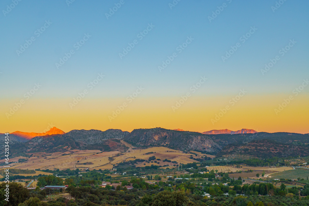 landscape of the valley of ronda at sunrise with the sky colored by the sun and the mountains illuminated with colors.