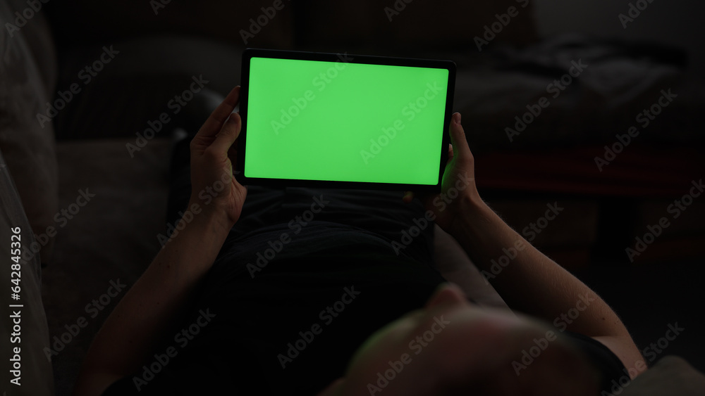Naklejka premium Man at home lying on a couch with tablet pc with green screen