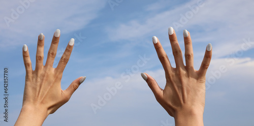 hands of the girl with polish on the nails and sky