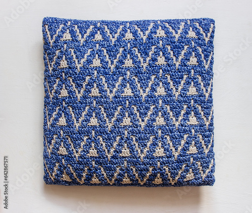 Blue white crochet pillow with abstract mosaic pattern on a white background. Top view.