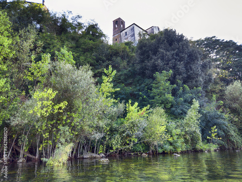 Glimpse near Bracciano lake at Anguillara Sabazia pittoresque village shore with transparent water and lush greenery and partial facade of ancient palace of ancient downtown