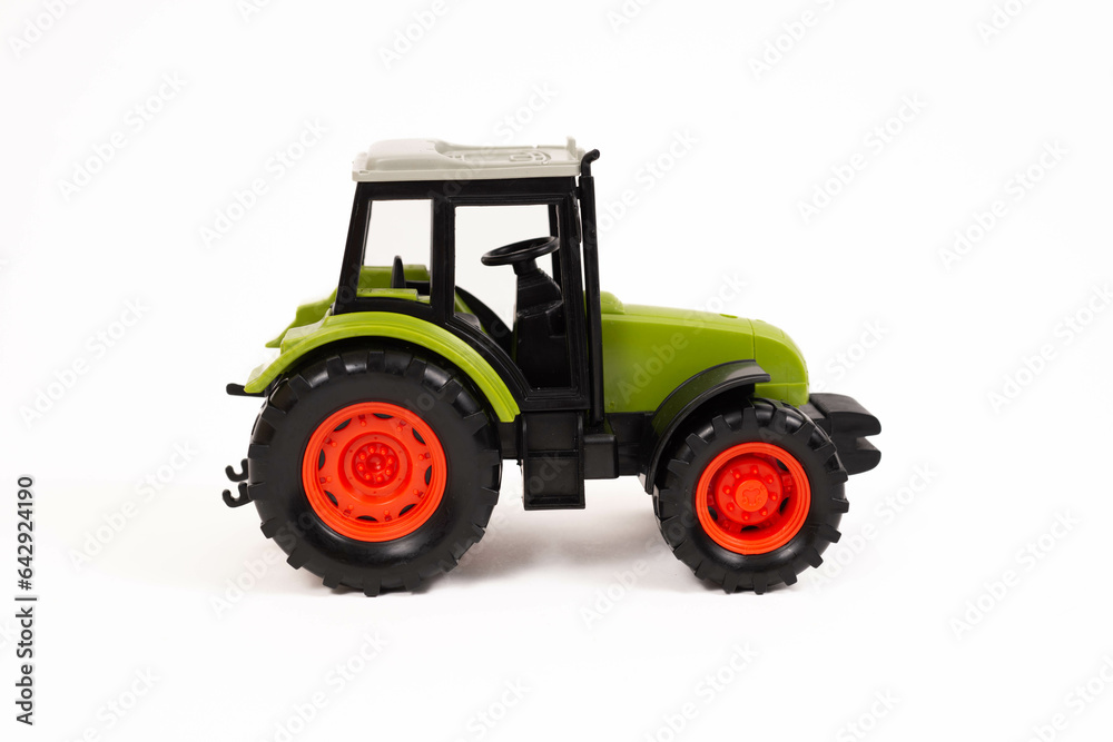 A green, orange and grey toy farm tractor isolated on a white background A green, orange and grey toy farm tractor isolated on a white background
