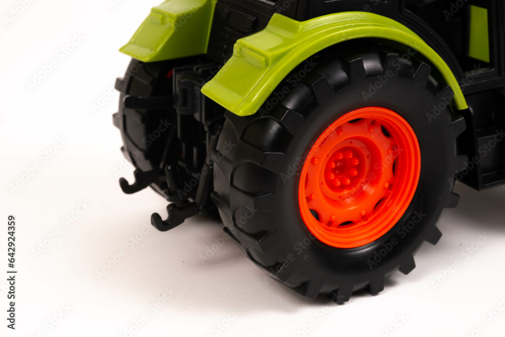 A green, orange and grey toy farm tractor isolated on a white background A green, orange and grey toy farm tractor isolated on a white background