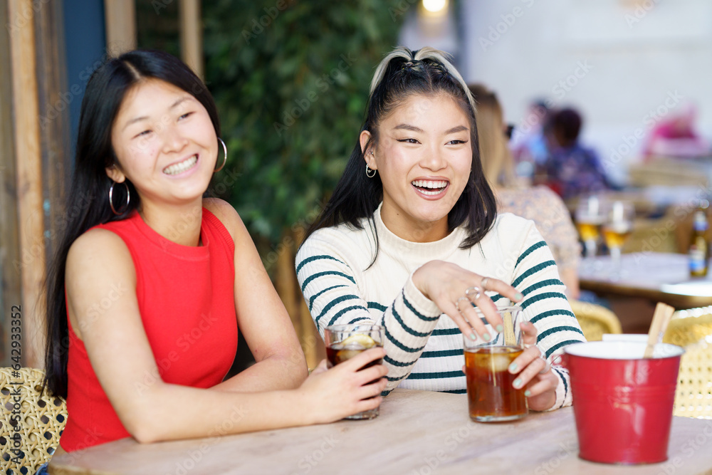 Obraz premium Positive Asian girls resting in cafe with drinks